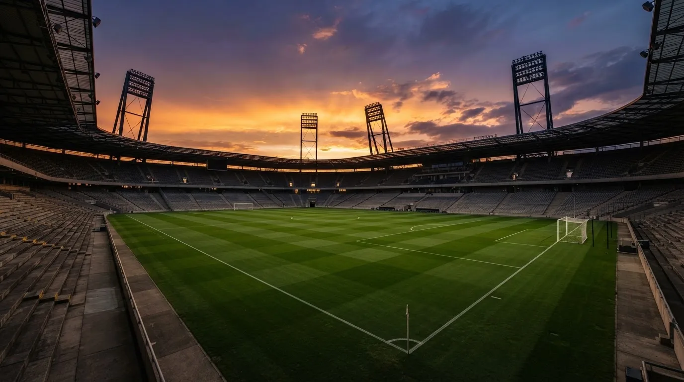 Un estadio de fútbol vacío con torres de iluminación al atardecer