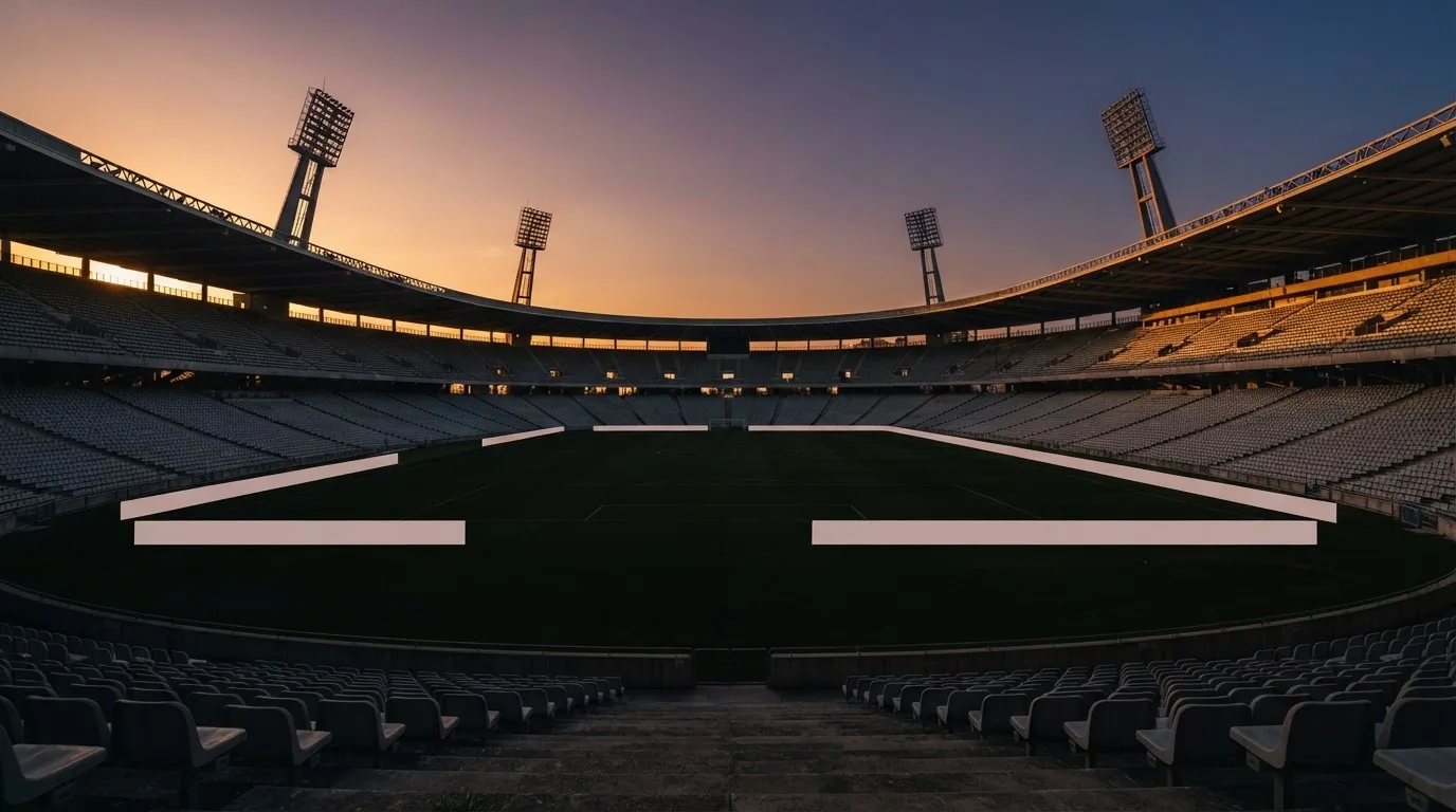 Un estadio de fútbol vacío con torres de iluminación al atardecer
