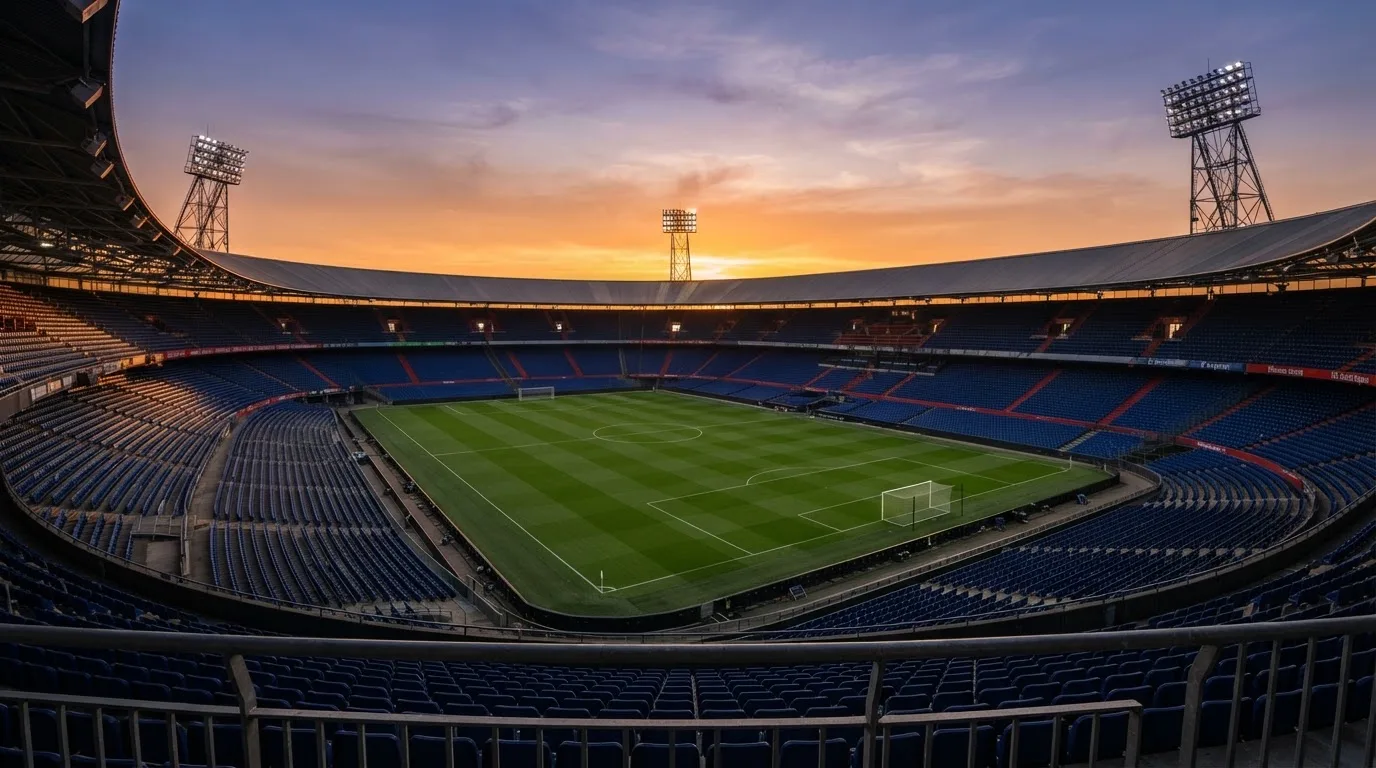 Un estadio de fútbol vacío con torres de iluminación al atardecer