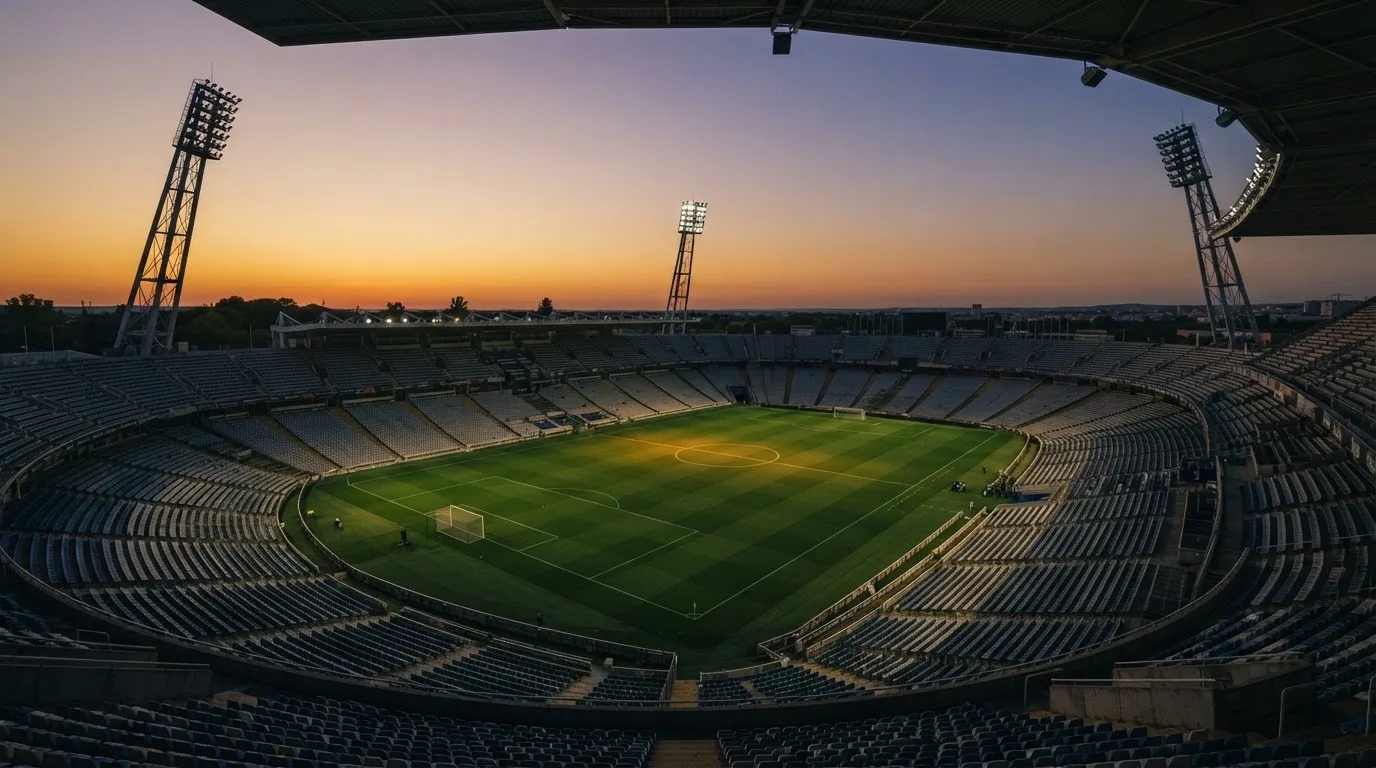 Un estadio de fútbol vacío con torres de iluminación al atardecer