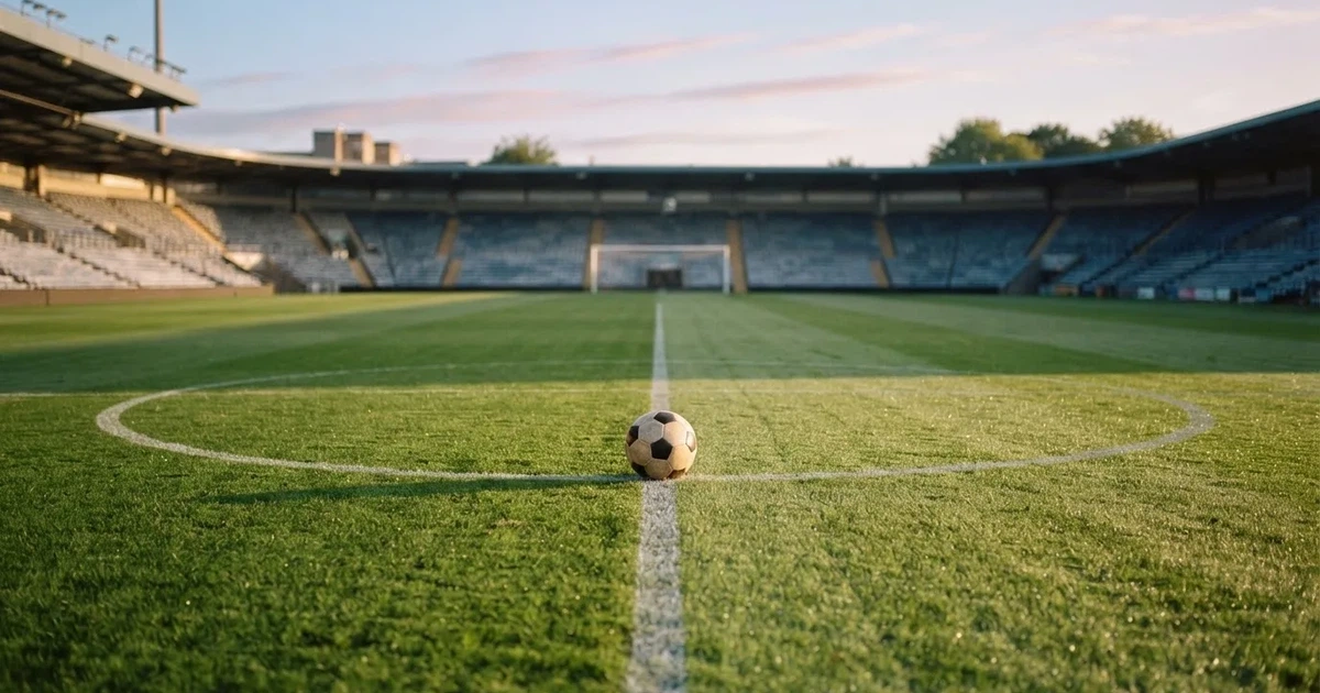 Un balón en el punto central de un campo de césped a la luz de la mañana