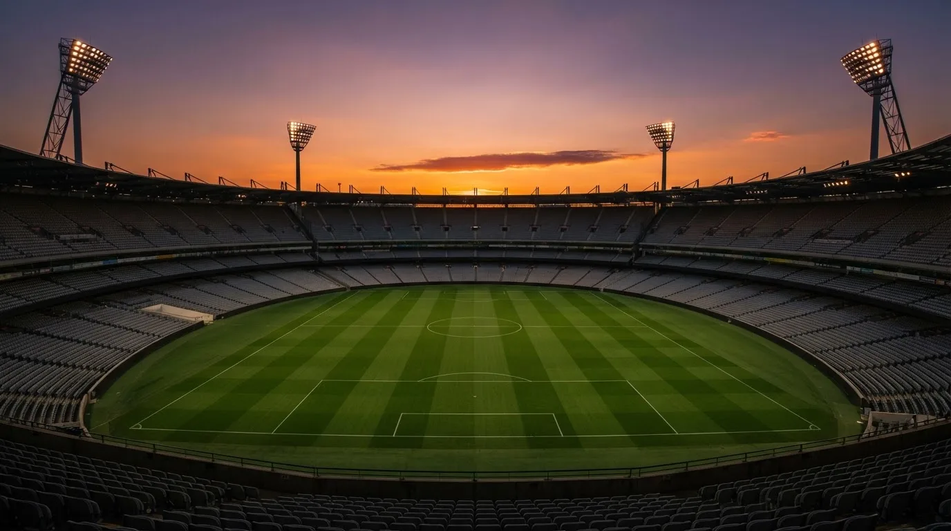Un estadio de fútbol vacío con torres de iluminación al atardecer