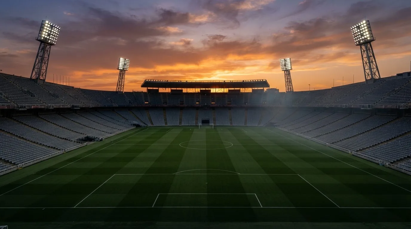Un estadio de fútbol vacío con torres de iluminación al atardecer