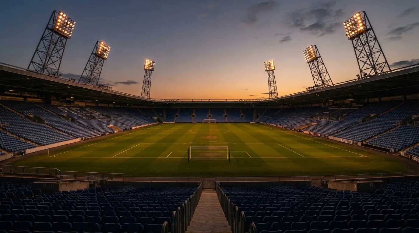 Un estadio de fútbol vacío con torres de iluminación al atardecer