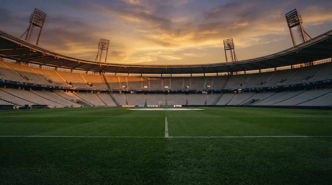 Un estadio de fútbol vacío con torres de iluminación al atardecer