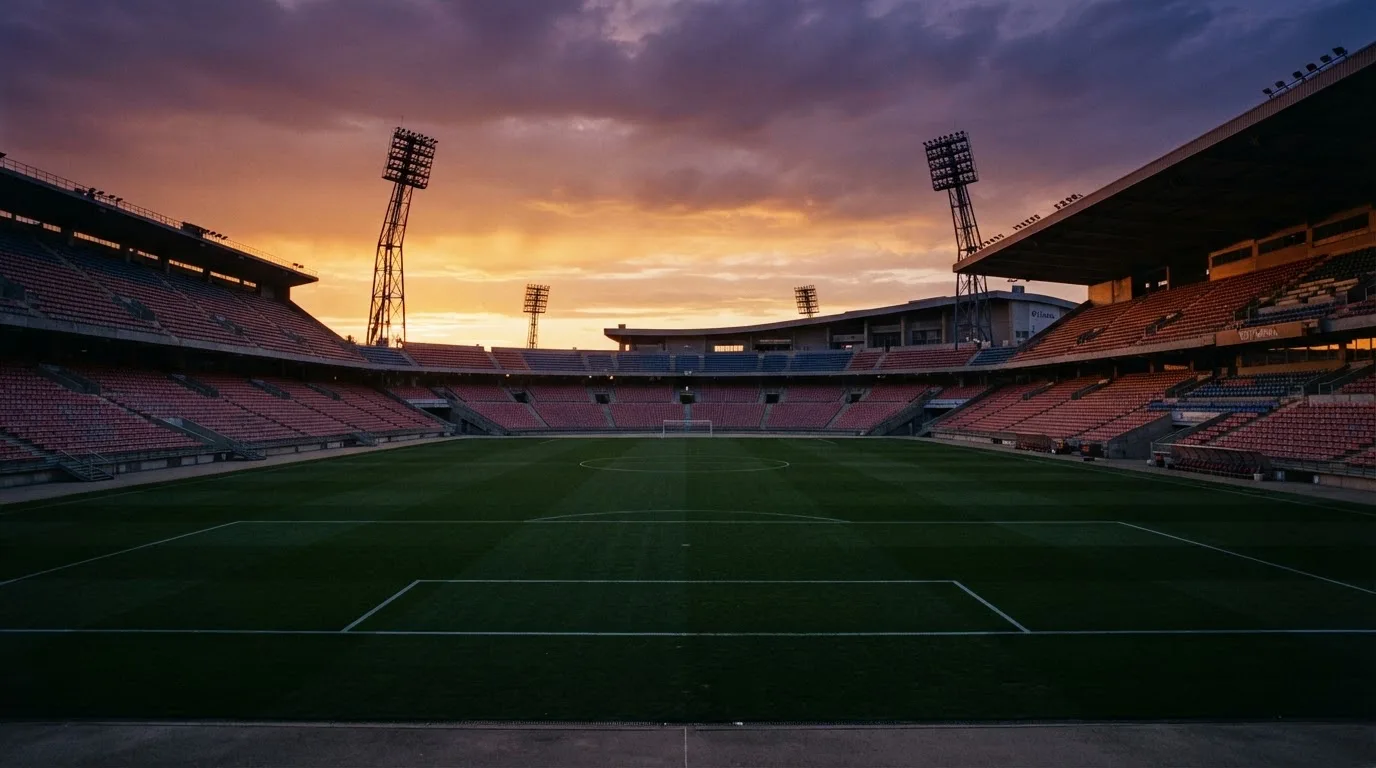 Un estadio de fútbol vacío con torres de iluminación al atardecer