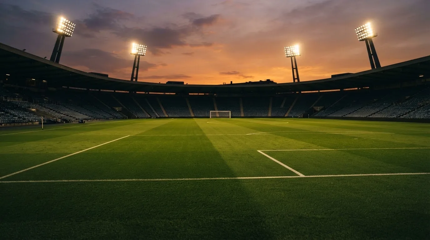 Un estadio de fútbol vacío con torres de iluminación al atardecer