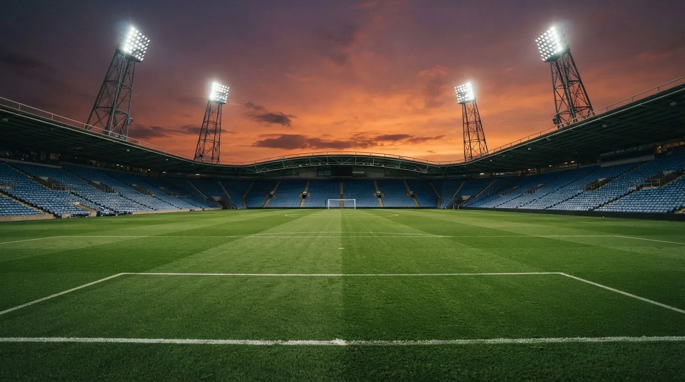 Un estadio de fútbol vacío con torres de iluminación al atardecer