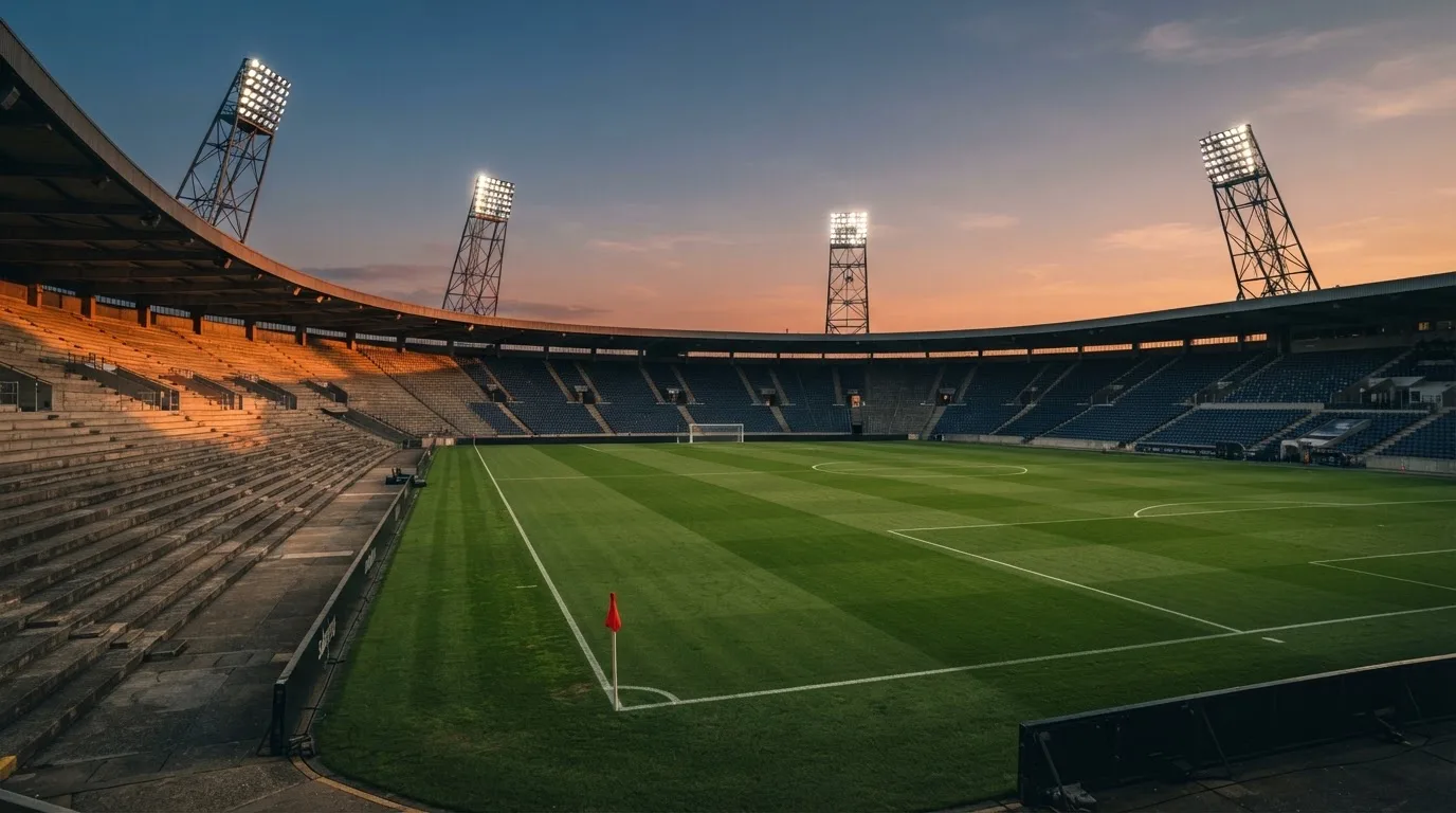 Un estadio de fútbol vacío con torres de iluminación al atardecer
