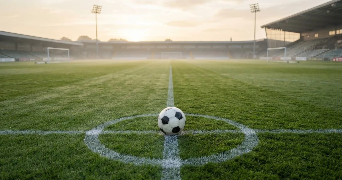 Un balón en el punto central de un campo de césped a la luz de la mañana