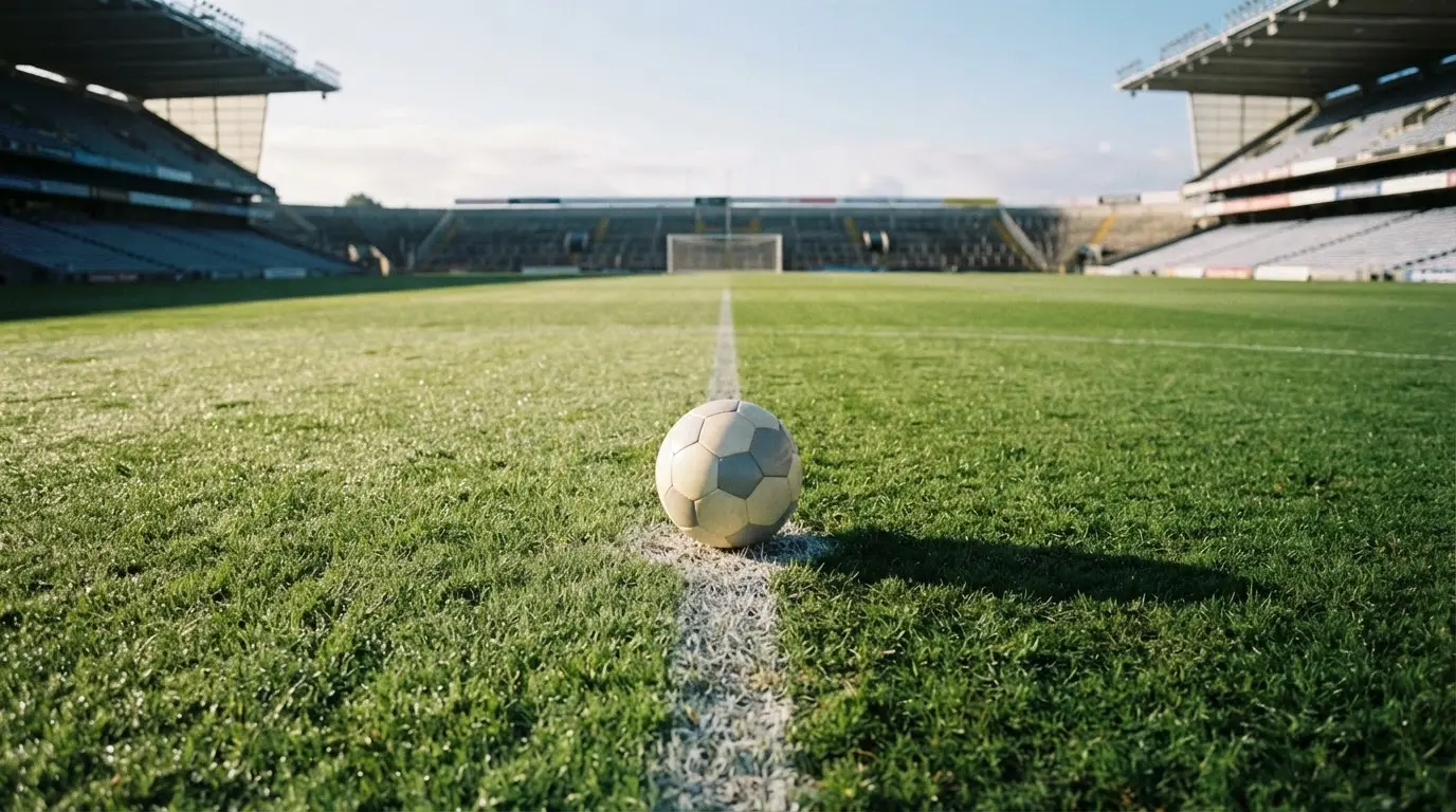 Un balón en el punto central de un campo de césped a la luz de la mañana