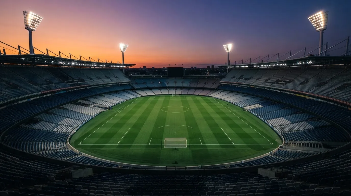 Un estadio de fútbol vacío con torres de iluminación al atardecer