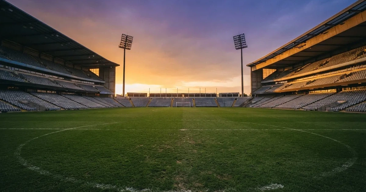 Un estadio de fútbol vacío con torres de iluminación al atardecer