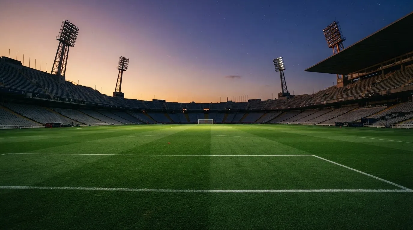 Un estadio de fútbol vacío con torres de iluminación al atardecer